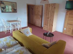 een woonkamer met een gele bank en een tafel bij Penzion Henke in Srbská Kamenice
