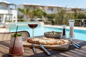 a table with a pizza and a glass of wine at Golden Sand in Plaka