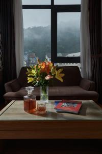 una sala de estar con una mesa con un jarrón de flores en Genuss Tam Dao - Hideaway Retreats, en Tam Ðảo