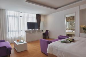 タムダオにあるGenuss Tam Dao - Hideaway Retreatsのベッドとテレビがあるホテルの部屋