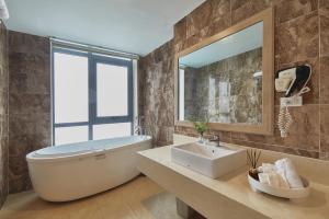 bagno con vasca, lavandino e specchio di Genuss Tam Dao - Hideaway Retreats a Tam Ðảo