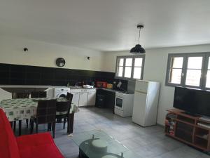 kuchnia z białymi urządzeniami i stołem z czerwoną kanapą w obiekcie Eco domaine 12hectares meublé pour 6 personnes w mieście Plouray