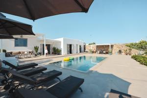 a house with a swimming pool with chairs and an umbrella at Villa Paraga in Platis Gialos