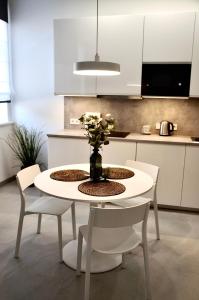 a white table with chairs and a vase with flowers at Mazvydo studio appartment in Klaipėda