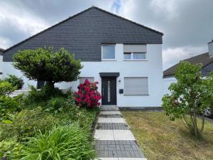 a white house with a black roof at Serene Meadows Apartment in Solingen
