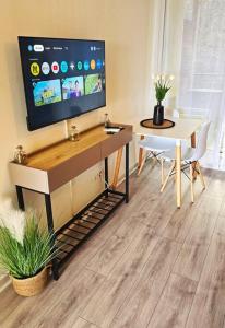 a living room with a table and a tv on a wall at Élégant studio Les Tourtereaux in Saint-Denis