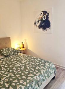 a bedroom with a bed and a painting on the wall at Élégant studio Les Tourtereaux in Saint-Denis