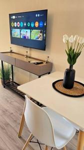 a white table with a vase of flowers and a tv at Élégant studio Les Tourtereaux in Saint-Denis