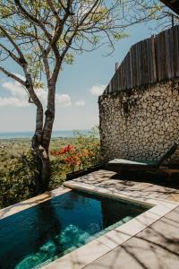 烏魯瓦圖的住宿－Divinity Villas - Uluwatu, Bali，一座游泳池,旁边是石墙和一棵树