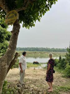 un hombre y una mujer de pie junto a un árbol en Bamby Chilling House - Feel The Nature en Sauraha