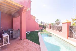 a backyard with a swimming pool and a pink house at Wehost-costaluz Casa Guayaba con piscina privada in El Puerto de Santa María
