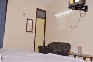 a bedroom with a chair and a tv on the wall at Hotel Viren Plaza Inn Agra in Agra