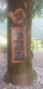 a sign on a tree with a board on it at Ristorante della Posta Carena in Carena