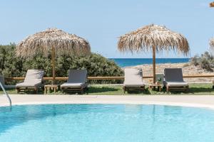 a group of chairs and umbrellas next to a swimming pool at Golden Sand in Plaka