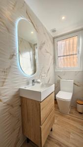 Un baño con lavabo, espejo e inodoro. en Boho Arenal Bol, en Calpe