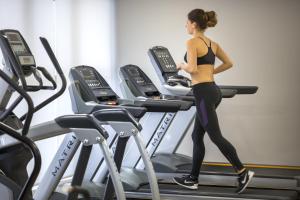 a woman running on a treadmill in a gym at Hotel Excelsior - Liburnia in Lovran
