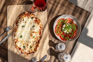 a pizza and a bowl of tomatoes and a glass of wine at Golden Sand in Plaka +47 photos