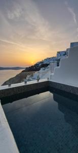 una piscina con puesta de sol en el fondo en Pegasus Spa Hotel, en Imerovigli