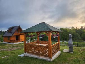 a wooden gazebo in a yard with a building at TAMARA - Brvnara za odmor in Han Pijesak