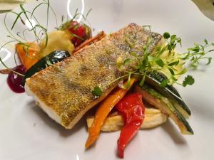 a white plate with a sandwich with vegetables on it at Juodasis Kalnas in Juodkrantė