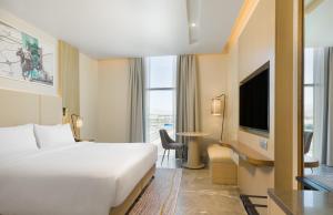 um quarto de hotel com uma cama e uma televisão em IntercityHotel Bawshar Muscat em Mascate