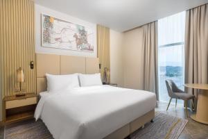 um quarto de hotel com uma cama grande e uma janela em IntercityHotel Bawshar Muscat em Mascate