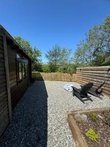 a backyard with a house and a chair and a fence at Cotts Cabin - Welcombe - 2 min walk to pub in Bideford