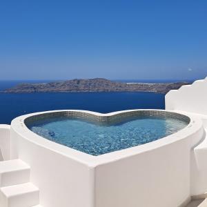a hot tub on the side of a white building at Pegasus Suites & Spa in Imerovigli