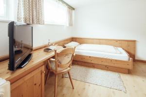 a bedroom with a desk with a bed and a television at KAISERS das kleine Stadthotel in Sonthofen