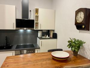 a kitchen with a wooden table with a clock on the wall at Wunderschönenes Apartament am Schlössle Zentrum Goldstadt in Pforzheim