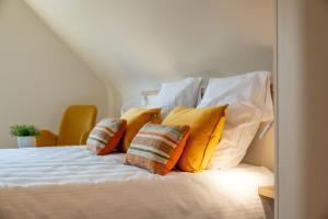 a bed with yellow and white pillows on it at Hoeve den Akker - luxueuze vakantiewoningen met privétuinen en alpaca's nabij Brugge, Damme, Knokke, Sluis en Cadzand in Damme