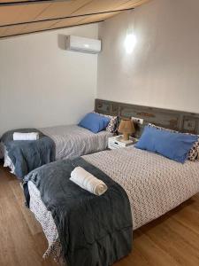 a room with three beds with blue pillows at Casa en el centro de Arahal in El Arahal