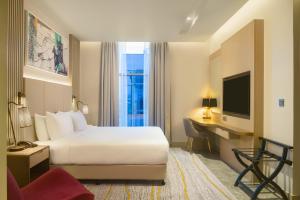 マスカットにあるIntercityHotel Bawshar Muscatのベッド、デスク、テレビが備わるホテルルームです。