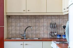 a kitchen with a sink and a tiled wall at DROSIA HOME in Skopelos Town