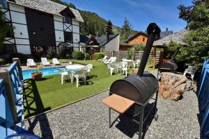 a grill in a backyard with a table and chairs at Plaza Mayor by Visionnaire in San Martín de los Andes