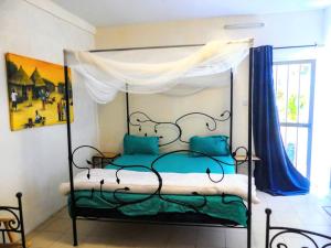 a bedroom with a canopy bed with blue pillows at Chez Sofia AFRO CHITI in Saint-Louis