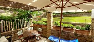 patio con tavolo, sedie e ombrellone di Confortevole Bilocale Giardino Doppio Parcheggio a Punta Ala