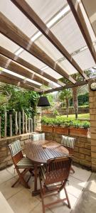 un patio con tavolo e sedie in legno sotto un pergolato di Confortevole Bilocale Giardino Doppio Parcheggio a Punta Ala