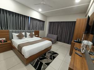 HOTEL ASIANA INN في أحمد آباد: غرفة نوم بسرير ومكتب وتلفزيون