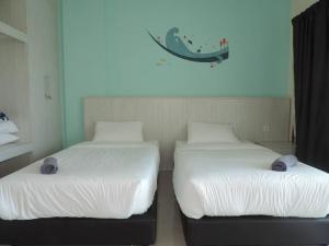 ルムットにあるMarina Island Seaview Homestayの部屋に並んで置かれた2つのベッド +1枚の写真