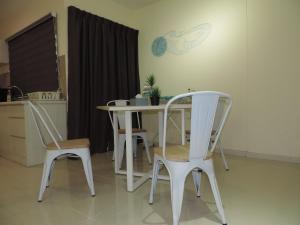 ルムットにあるMarina Island Seaview Homestayのテーブルと椅子付きのキッチン(壁掛け時計付)