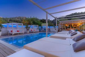 a row of white beds sitting next to a swimming pool at Hotel Boutique Minister 4Sup in Port de Soller
