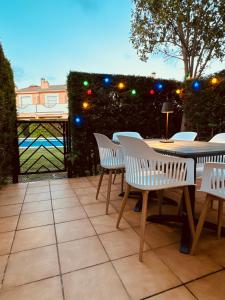 a patio with white chairs and a table and a fence at La Bella Lola Estartit Rental in L'Estartit