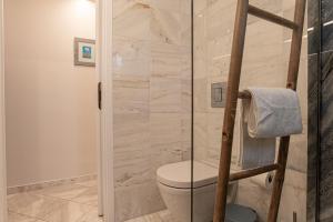 a bathroom with a toilet and a glass shower at Feliz Apt- Breathtaking Seaview and Sunset by ΜΡS in Anavyssos +25 photos