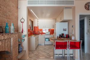 a kitchen with red chairs and a white refrigerator at Feliz Apt- Breathtaking Seaview and Sunset by ΜΡS in Anavyssos