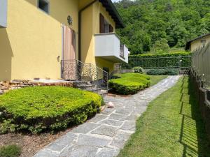 a house with a stone walkway next to a yard at ACERO ROSSO in Cortenova