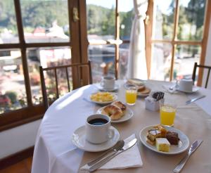 Hotel Caupolican by Visionnaire في سان مارتين دي لوس أندس: طاولة مع أطباق من الطعام وكوب من القهوة