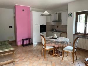 a kitchen with a table and chairs and a pink wall at ACERO ROSSO in Cortenova