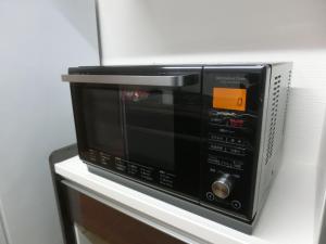 a microwave sitting on a shelf in a room at 松田 Terrace A in Ginoza