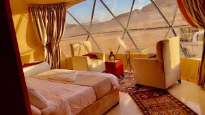 a room with a bed and two chairs and a window at Xperience golden rum camp in Wadi Rum